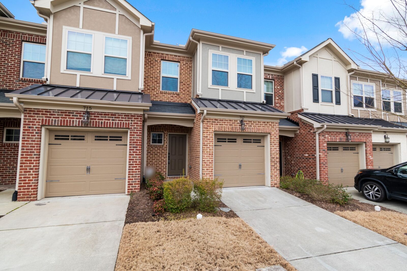 Row of attached two-storey brick townhouses, each with a single garage and its own driveway