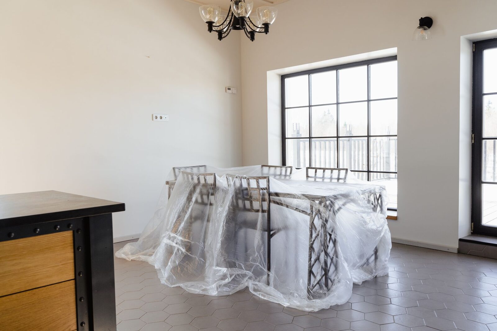 Dining table and chairs wrapped in plastic sheeting in a room under renovation