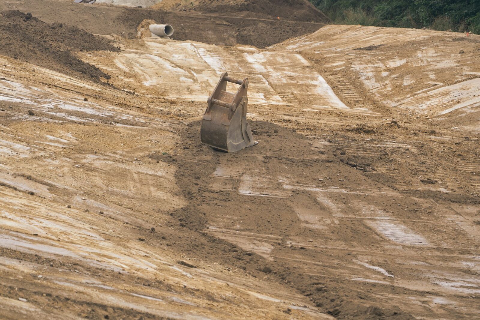 Excavator bucket resting on freshly graded earth embankments